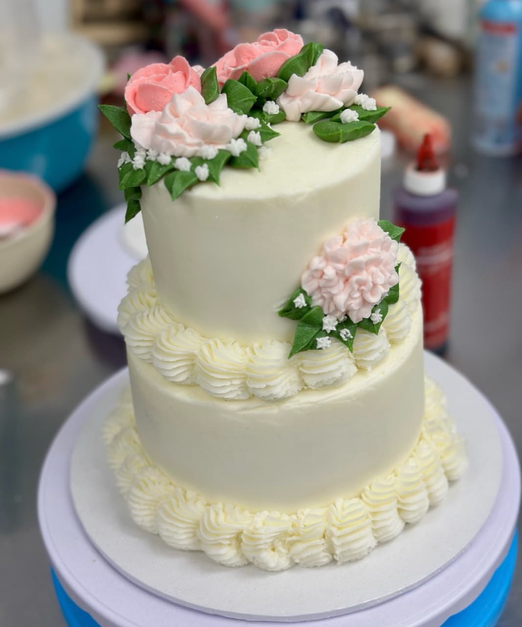 Two-tier custom celebration cake decorated with pink buttercream flowers