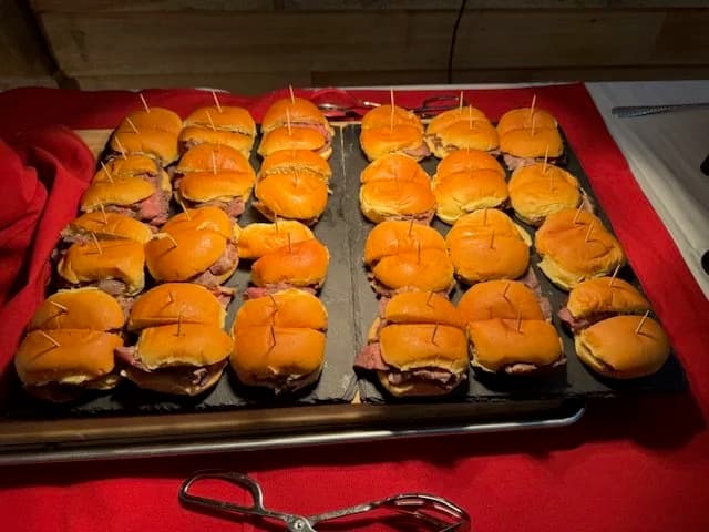 A tray of petite meat sliders secured with toothpicks.