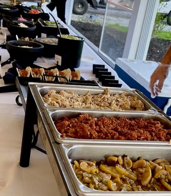 A catered buffet with fried chicken, shredded turkey, vegetables, side dishes, and toppings.