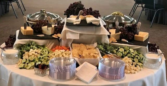 A salad and cheese platter with grapes, crackers, and vegetables.