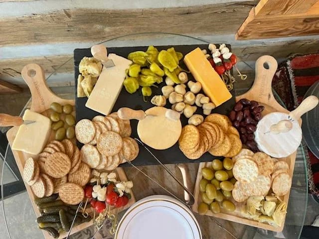 Wooden platters filled with cheeses, crackers, grapes, pickles, and vegetables.