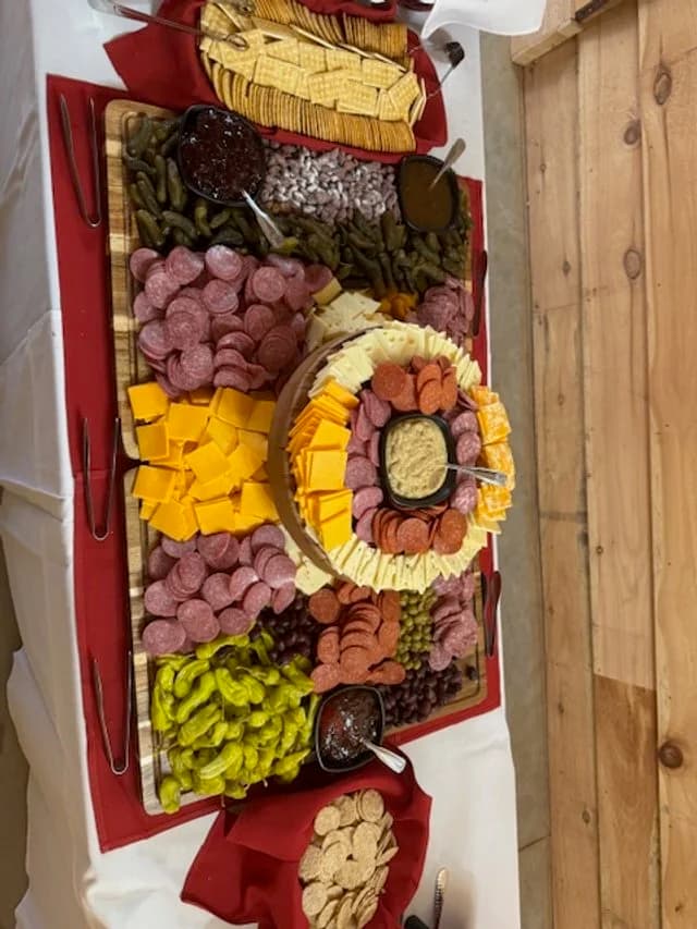 A charcuterie table with cheeses, cured meats, grapes, pickles, crackers, and dips.