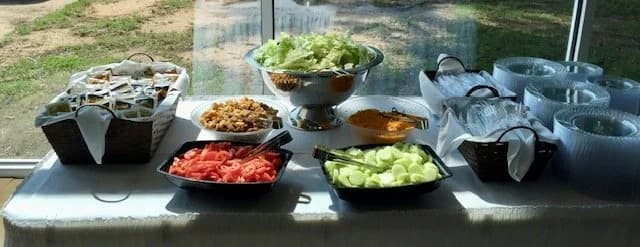 A salad bar with lettuce, tomatoes, cucumbers, and assorted toppings.
