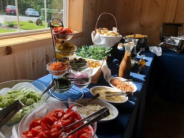 A salad buffet with toppings and condiments beside a bright window.