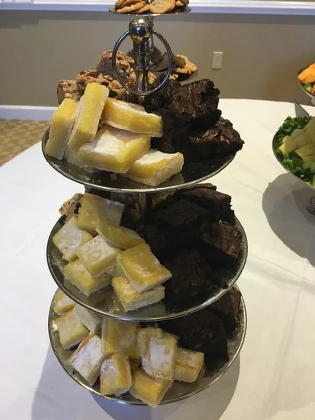 A three-tier serving stand with lemon bars and brownies.