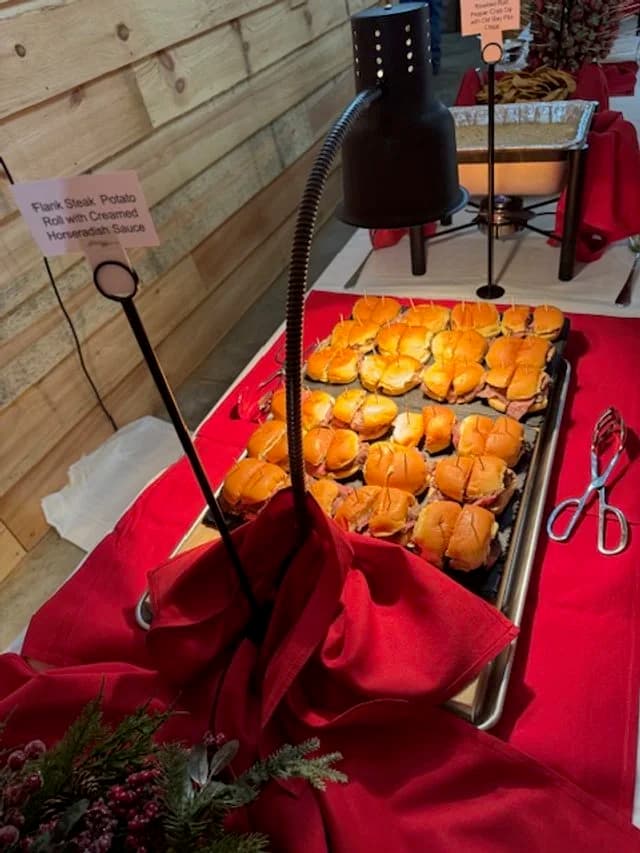 A tray of petite sandwiches served beneath a warming lamp.