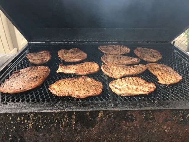 Several steaks cooking over a barbecue grill.